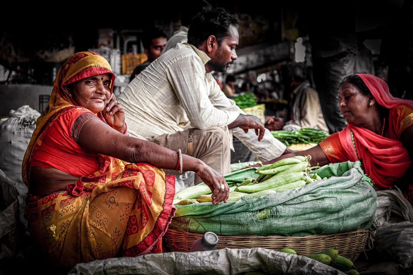 A smiling vendor among fresh vegetables at a local market