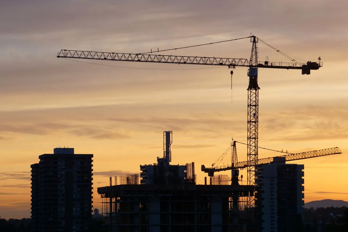 A tower crane over a building site at sunset