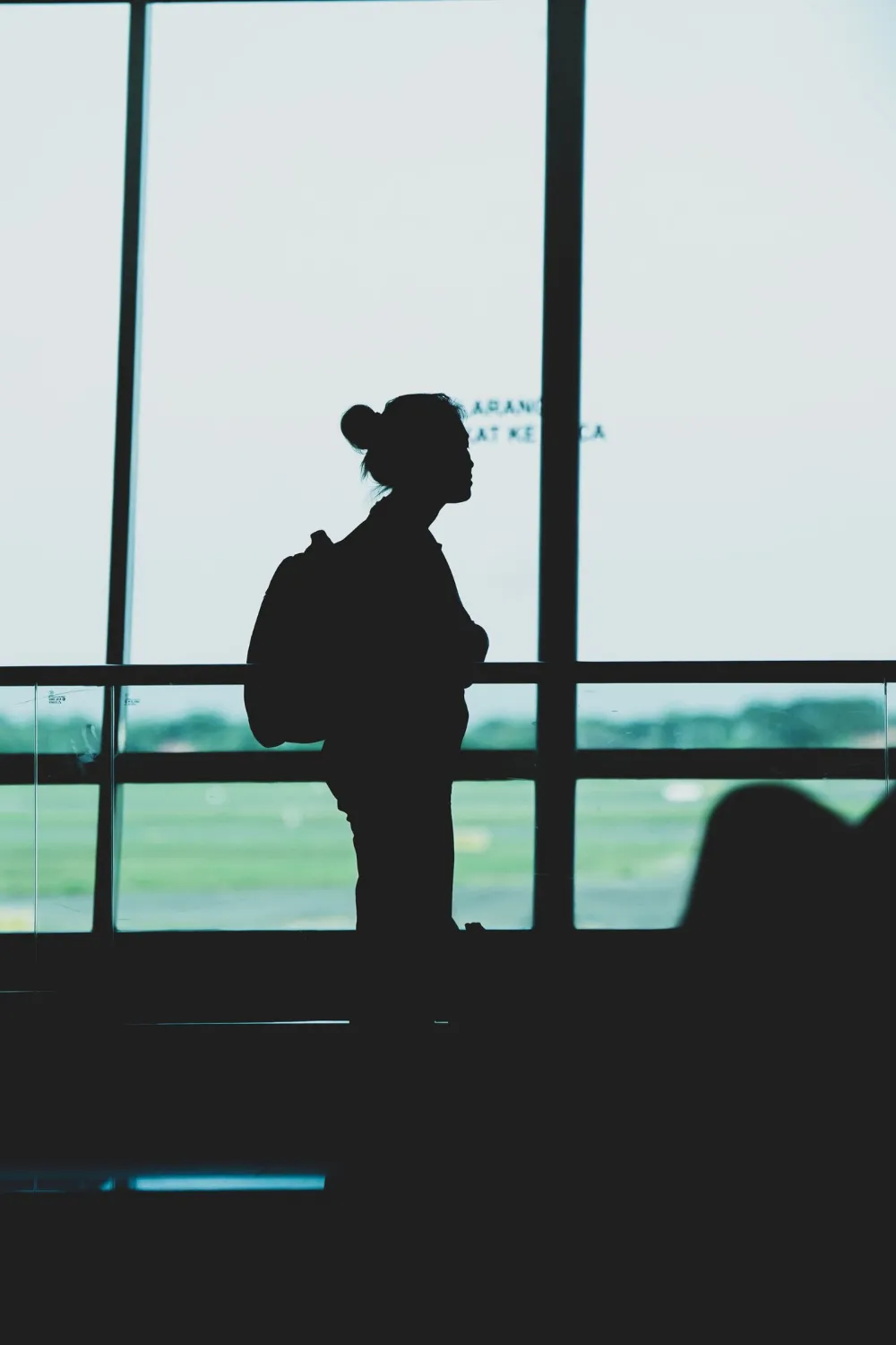 A student with a backpack at an airport terminal window