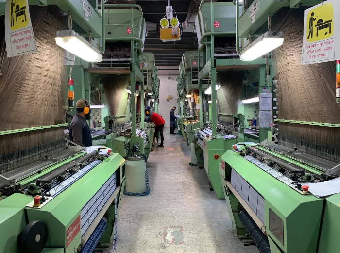 Workers tending rows of looms in a textile mill