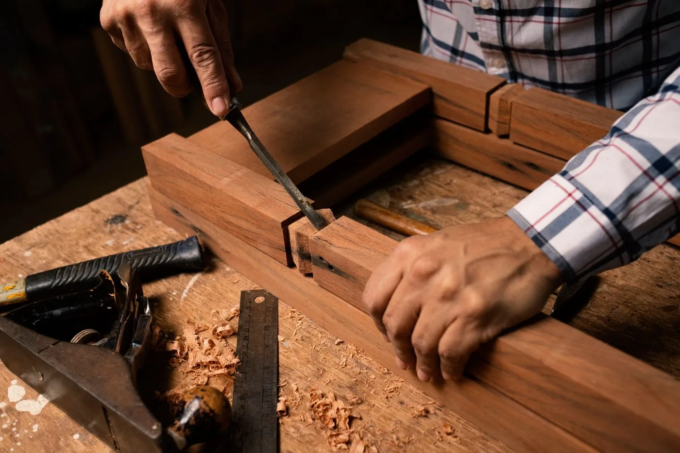 A craftsman's hands shaping wood with a chisel