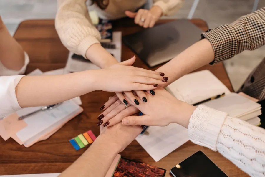 Colleagues joining hands across a table