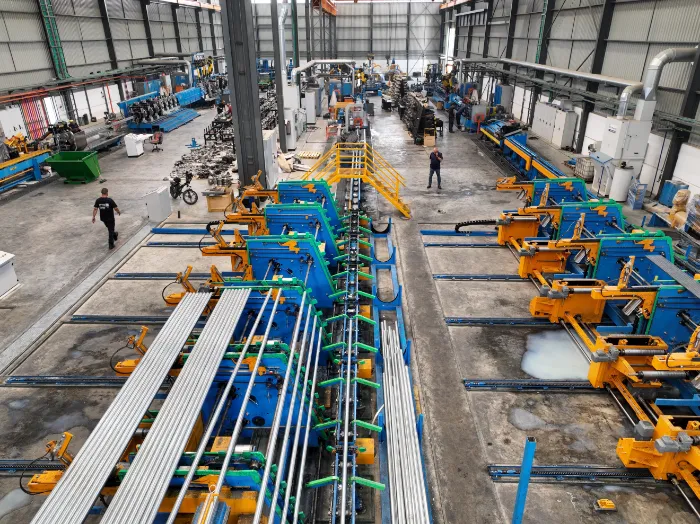 A long steel-pipe production line in a factory hall, seen from above